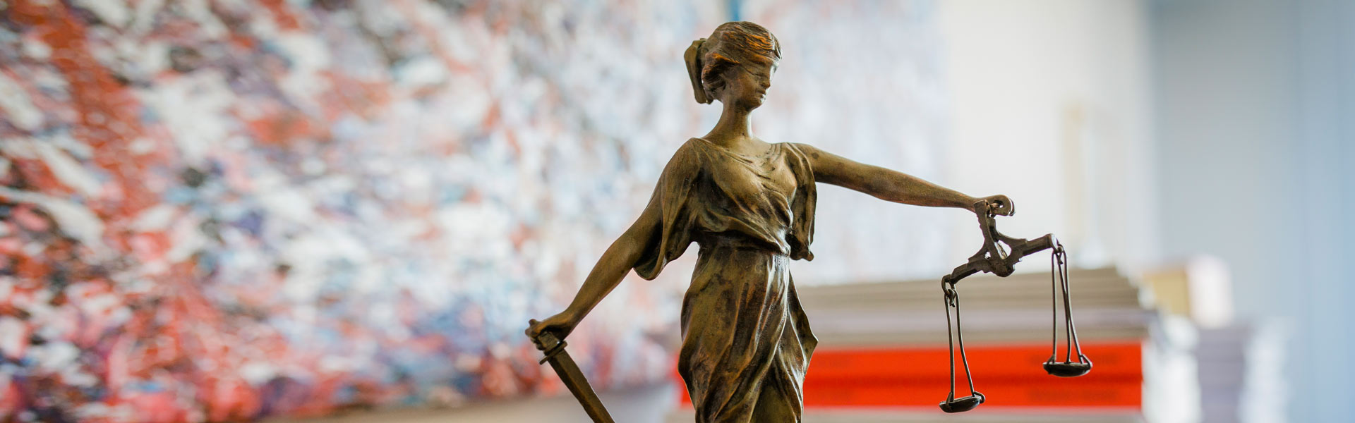 Steuerberater-Haag+Rechtsberatung Justitia-Figur vor einem Stapel mit Unterlagen