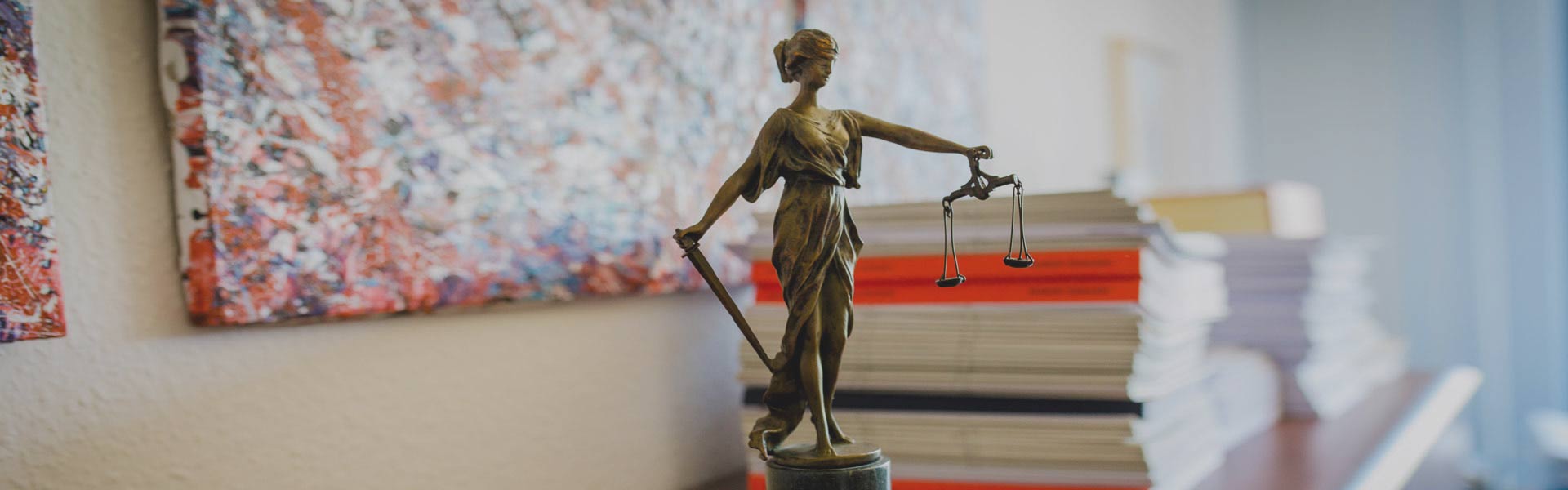 Justitia-Figur vor einem Stapel mit Unterlagen