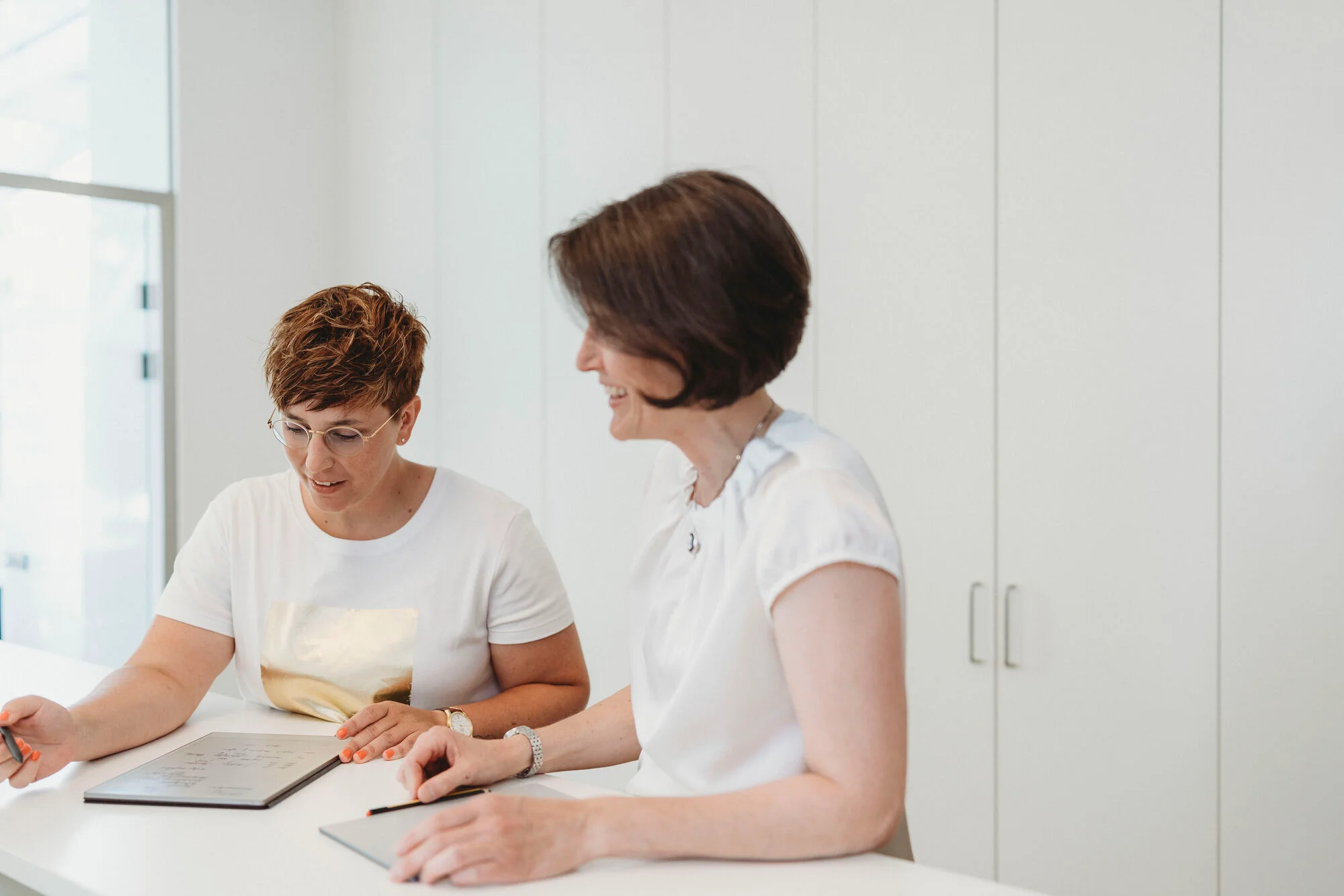 Frauen stehen vor Dokumenten und schauen diese an